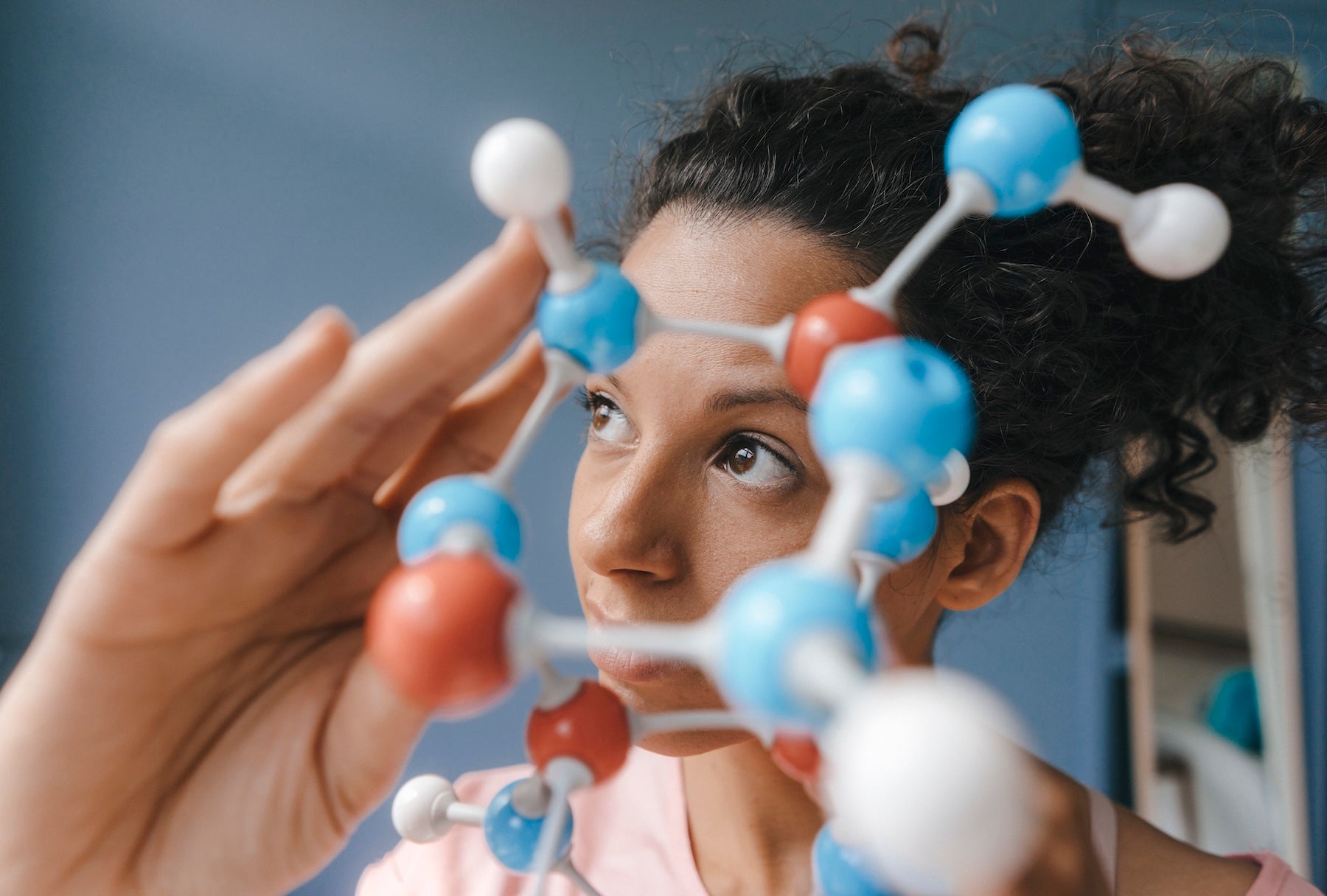 Female scientist holding a molecule model — the evolved science behind High-Demand Amino Acids (HDAA) supplements