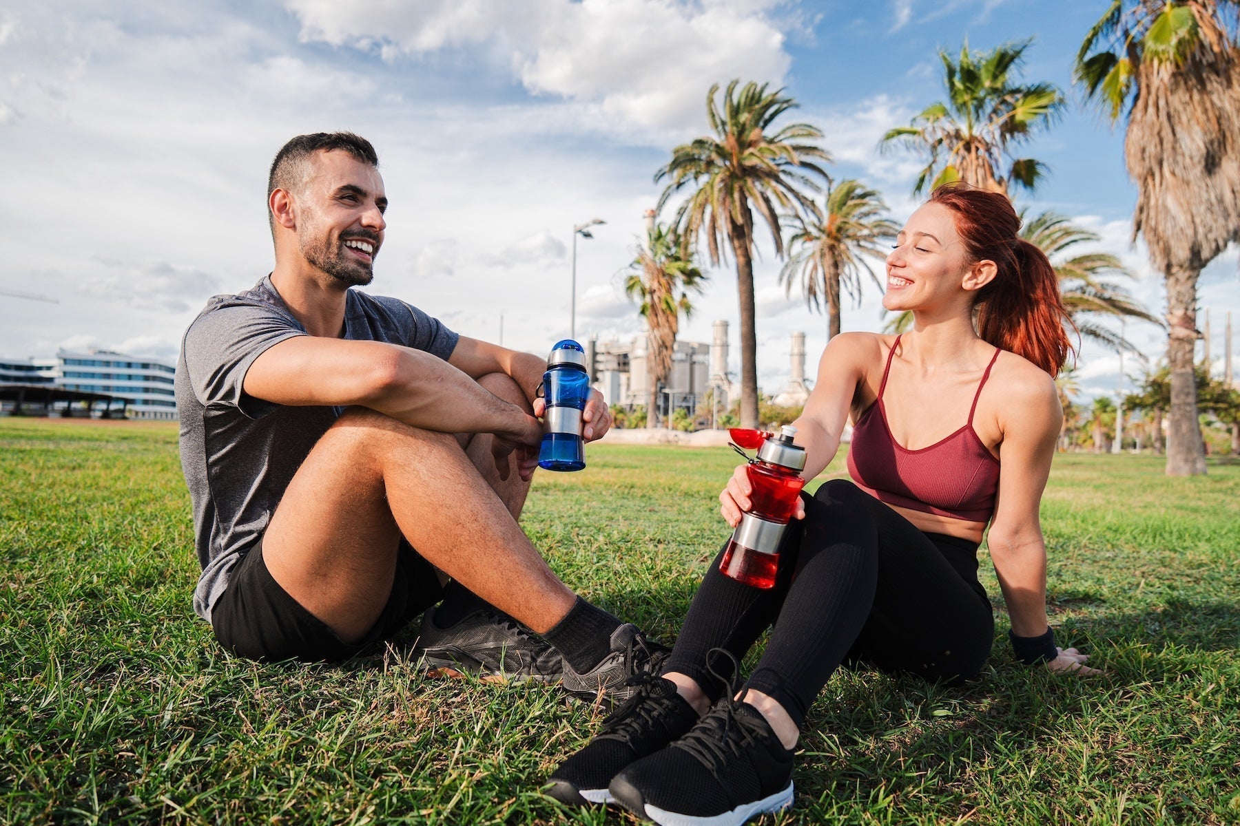 Athletic couple resting on grass and hydrating after exercise — HDAA vs BCAA comparison for the future of amino acid supplements