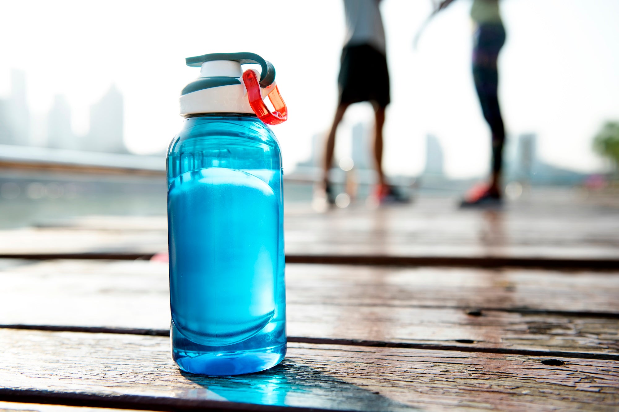 Blue water bottle on a wooden surface with blurred people in the background